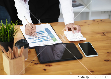 A businesswoman using pen point to chart document is researching earnings affected by the coronavirus pandemic to adjust her market strategy A businesswoman using pen point to chart document is researching earnings affected by the coronavirus pandemic to adjust her market strategy 95899942