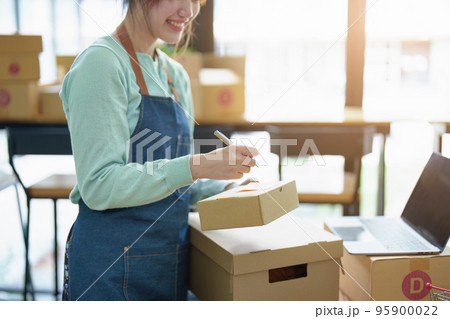 A portrait of a small startup, and SME owner, an Asian female entrepreneur, is writing down information on a notepad to organize the product before packing it into the inner box for the customer. A portrait of a small startup, and SME owner, an Asian female entrepreneur, is writing down information on a notepad to organize the product before packing it into the inner box for the customer. 95900022