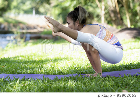 Young woman doing yoga exercises on the outdoor lawn. Young woman doing yoga exercises on the outdoor lawn. 95902065