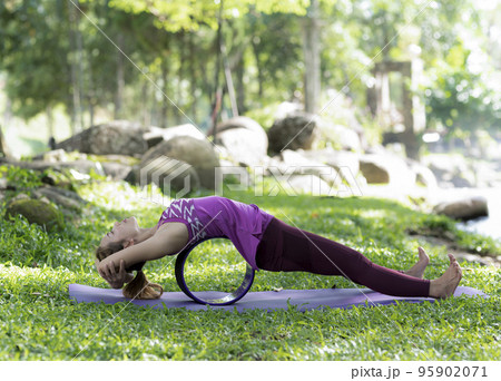 Young woman doing yoga exercises on the outdoor lawn. Young woman doing yoga exercises on the outdoor lawn. 95902071