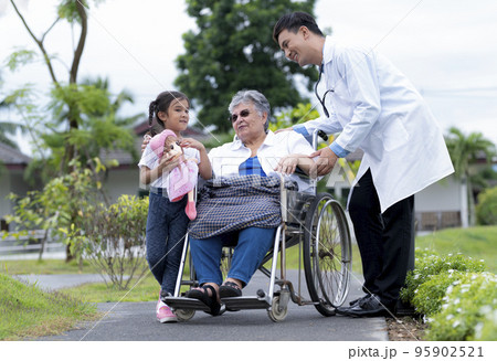 A young asian doctor and a young girl take care of an elderly middle eastern woman in a wheelchair. A young asian doctor and a young girl take care of an elderly middle eastern woman in a wheelchair. 95902521