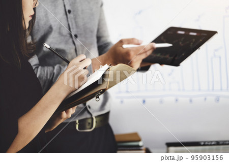 Woman using pen for note with An investment expert points a pen at a tablet monitor to analyze the stock market to teach you how to make a profit Woman using pen for note with An investment expert points a pen at a tablet monitor to analyze the stock market to teach you how to make a profit 95903156