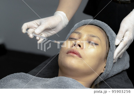 A young woman injects vitamins into her face in a beauty clinic. A young woman injects vitamins into her face in a beauty clinic. 95903256
