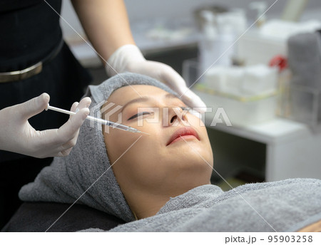 A young woman injects vitamins into her face in a beauty clinic. 95903258