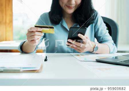 Portrait of young Asian woman using credit card and phone for online shopping. Portrait of young Asian woman using credit card and phone for online shopping. 95903682