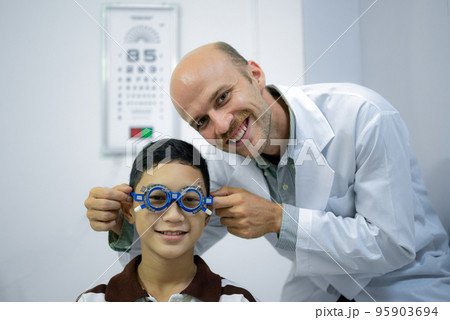 Boy has his eyes checked for glasses by a specialist. 95903694