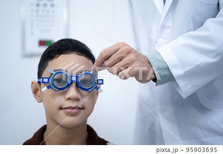 Boy has his eyes checked for glasses by a specialist. 95903695