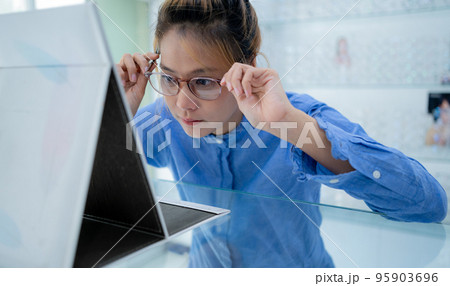 The girl tried on the glasses and looked in the mirror. 95903696