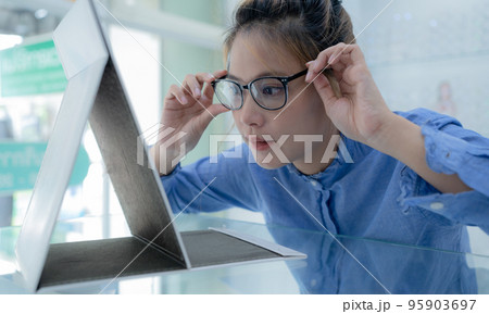 The girl tried on the glasses and looked in the mirror. 95903697