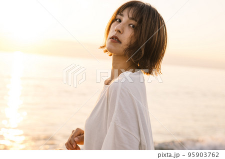 夕焼けの海に立つ女性ポートレート・ビューティー 95903762