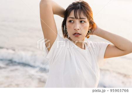 夕焼けの海に立つ女性ポートレート・ビューティー 95903766