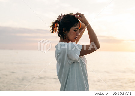 夕焼けの海に立つ女性ポートレート・ビューティー 95903771