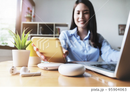 focus Female hand holding Smartphone to Charging at Wireless fast Charging pad at work. vintage tone focus Female hand holding Smartphone to Charging at Wireless fast Charging pad at work. vintage tone 95904063