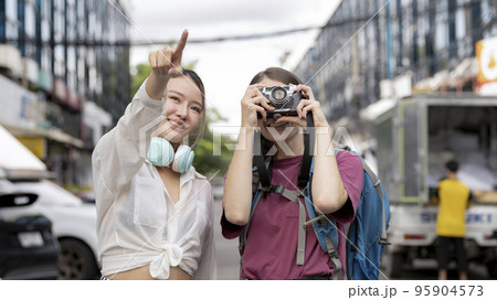 Two women of different nationalities travel happily. 95904573