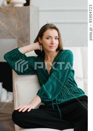 Stylish trendy looking young lady dressed in fashionable wear having relaxed look while resting indoors in comfortable armchair Stylish trendy looking young lady dressed in fashionable wear having relaxed look while resting indoors in comfortable armchair 95904723
