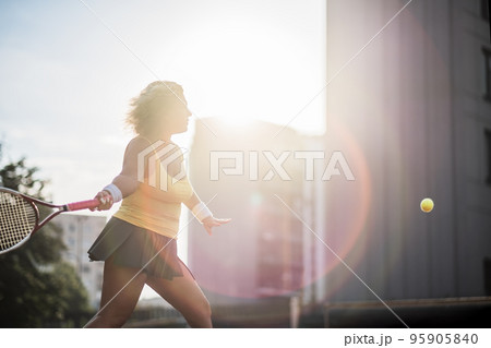 Caucasian mature woman playing tennis outside on sunny day. 95905840