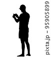 A black silhouette of a man in a cap who is photographing something on the phone. 95905899