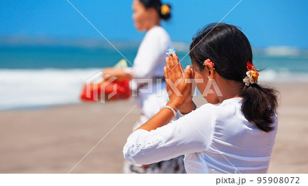 Young balinese women praying with namaste hands on sea beach Young balinese women praying with namaste hands on sea beach 95908072