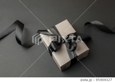 Craft gift box on a dark background, decorated with a textured bow, creating a romantic luxury atmosphere. For birthday, anniversary presents, gift post cards, banner, flyer, invitation, voucher 95909327
