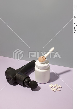 Therapeutic percussive massage gun, fit meal, pills, sport energy bar, protein on gray background - concept of modern sport activity and diet, health lifestyle routine, wellness, healthcare copy space 95909608