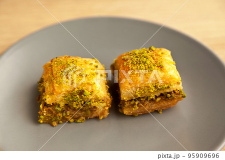 Baklava with pistachio, one of the most beautiful desserts of Turkish cuisine, in gray plate, on oak cutting board 95909696