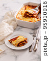 Fresh lasagna with meat and tomato sauce baked in the oven in a ceramic dish. 95910916