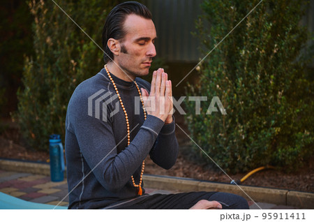 Close-up portrait of peaceful man yogi practicing yoga outdoors, meditating, putting palms together. Meditation. Yoga practice. Mindfulness. Prayer and gratitude. Spiritual growth. Health. Body care 95911411