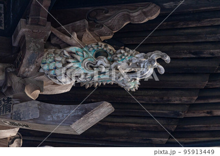 お寺の軒下に装飾された龍の顔 95913449