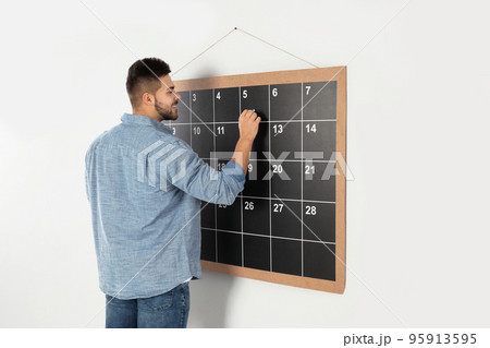 Young man writing with chalk on board calendar 95913595
