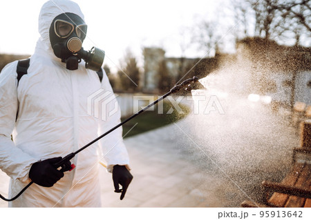 Man in virus protective suit and mask disinfects public places. Infection prevention and control. 95913642
