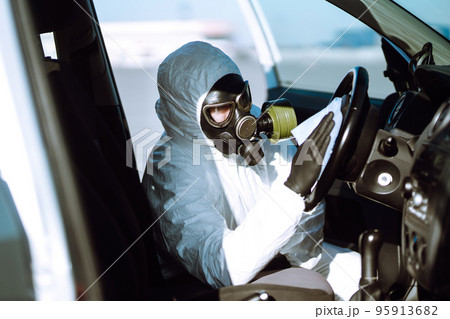 Hand of Man in protective suit washing and disinfection of the steering wheel in the car Hand of Man in protective suit washing and disinfection of the steering wheel in the car 95913682