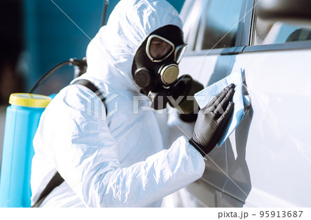 Hand of Man in protective suit washing and disinfection handles of a car.Pandemic in quarantine city 95913687
