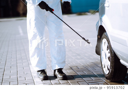 Man in protective suit washing and disinfection car wheels, to preventing the spread of the epidemic 95913702