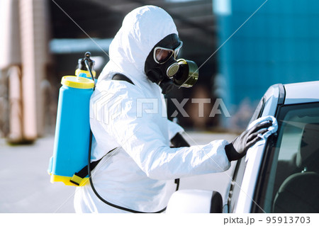 Hand of Man in protective suit washing and disinfection handles of a car. 95913703