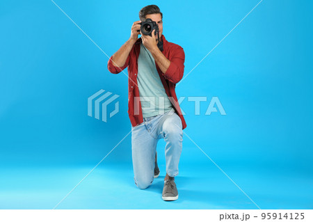 Professional photographer working on light blue background in studio Professional photographer working on light blue background in studio 95914125