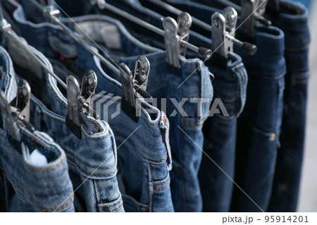 Metal hangers with different stylish jeans, closeup Metal hangers with different stylish jeans, closeup 95914201