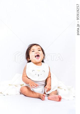 白背景の前に座り笑う1人の女の子の赤ちゃん> 95919257