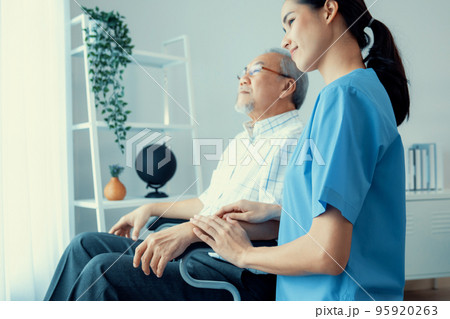Caring nurse and a contented senior man in a wheel chair at home. 95920263