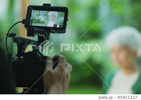 シニア女性の映像を撮影するカメラマン シニア女性の映像を撮影するカメラマン 95921327