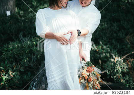 妊婦の奥さんのお腹に手を添える旦那さん 95922184