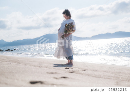 ビーチでブーケを持って立っている妊婦さん 95922218