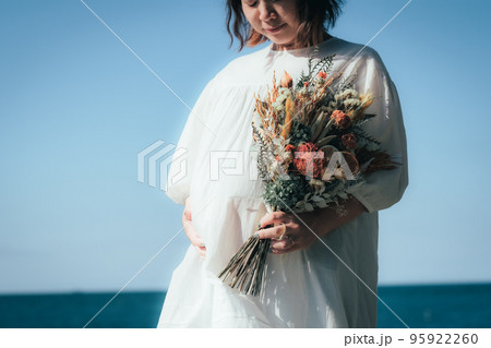 海辺でブーケを持つ妊婦さん 95922260