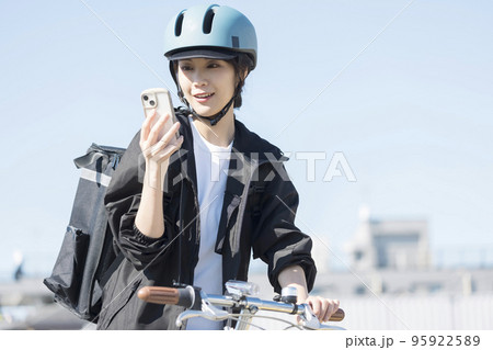 フードデリバリーイメージ　届け先をスマホでチェックする配達員女性 95922589