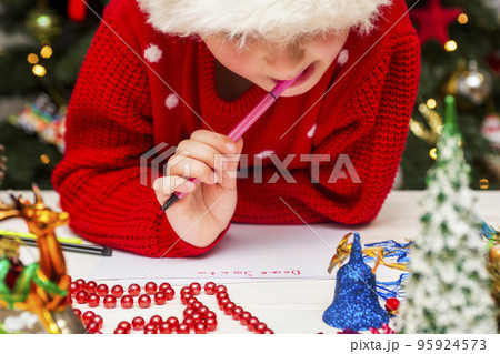 Little child is writing letter to Santa Claus at table Little child is writing letter to Santa Claus at table 95924573