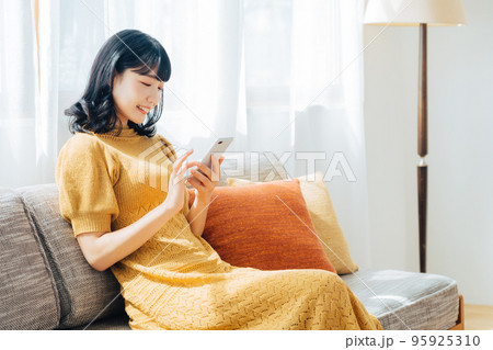 ソファに座ってスマホを使う女性 ソファに座ってスマホを使う女性 95925310