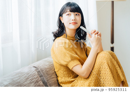 ソファに座ってスマホを使う女性 ソファに座ってスマホを使う女性 95925311