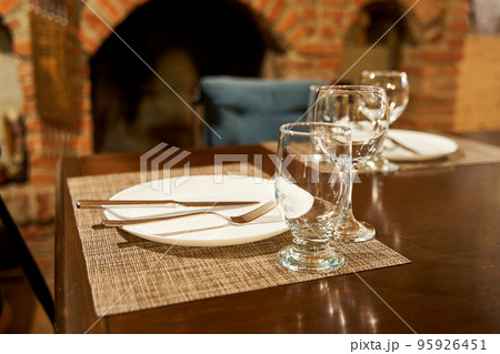 A table with clean dishes in a cozy cafe with a fireplace 95926451