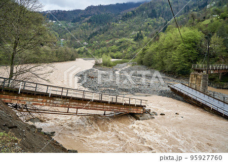 A bridge over a mountain river destroyed by water 95927760
