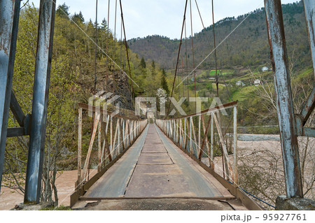 Wobbly old bridge over a mountain river for cars. Wobbly old bridge over a mountain river for cars. 95927761