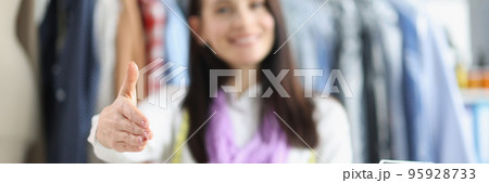Woman seamstress giving hand for handshaking, bright sewing accessories on table Woman seamstress giving hand for handshaking, bright sewing accessories on table 95928733